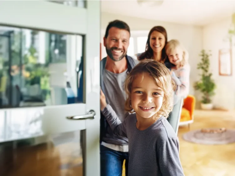 Familie mit zwei Kinder schauen durch eine geöffnete Tür